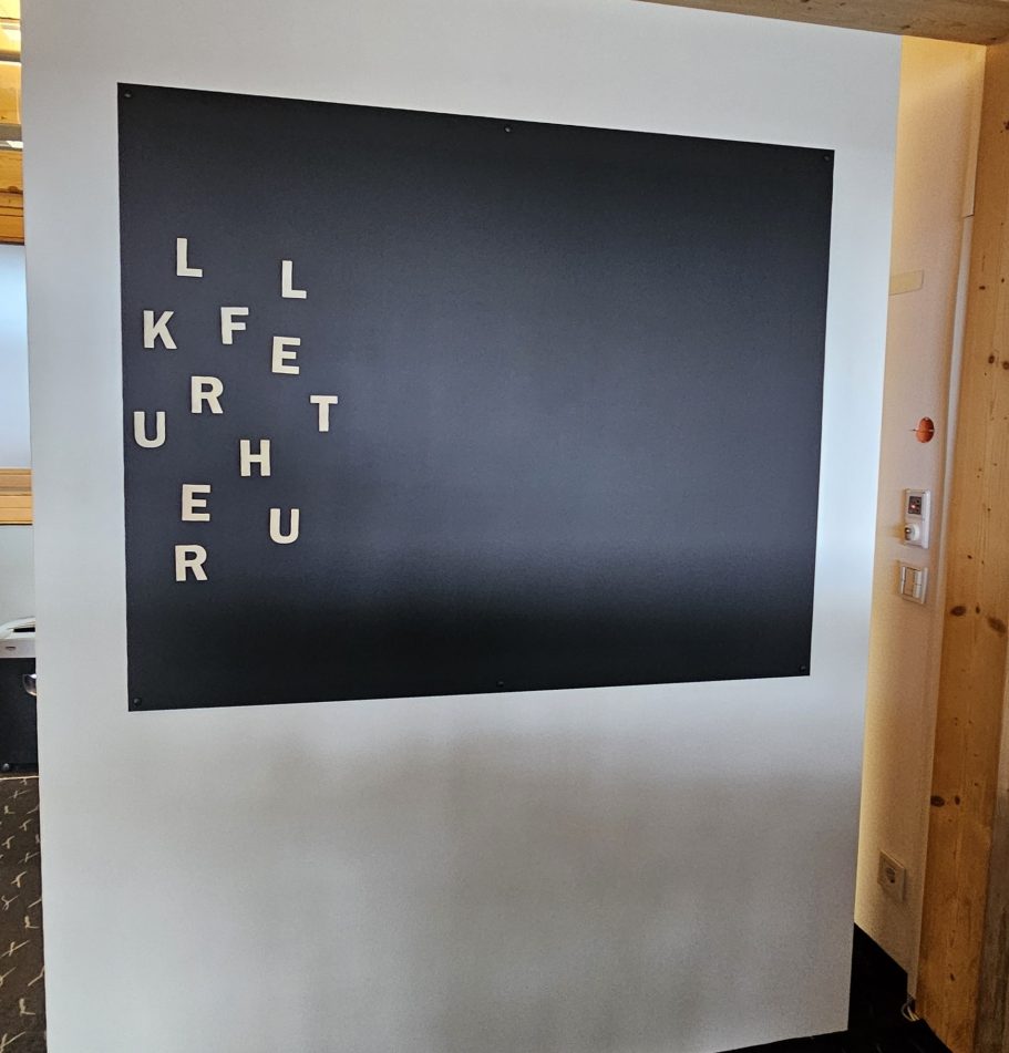 Holzbuchstaben auf Magnettafel Schwarze Kreidetafel mit magnetischen Holzbuchstaben in einer kreativen Anordnung.